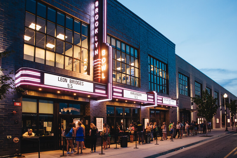 The exterior of Brooklyn Bowl. People are standing in line.