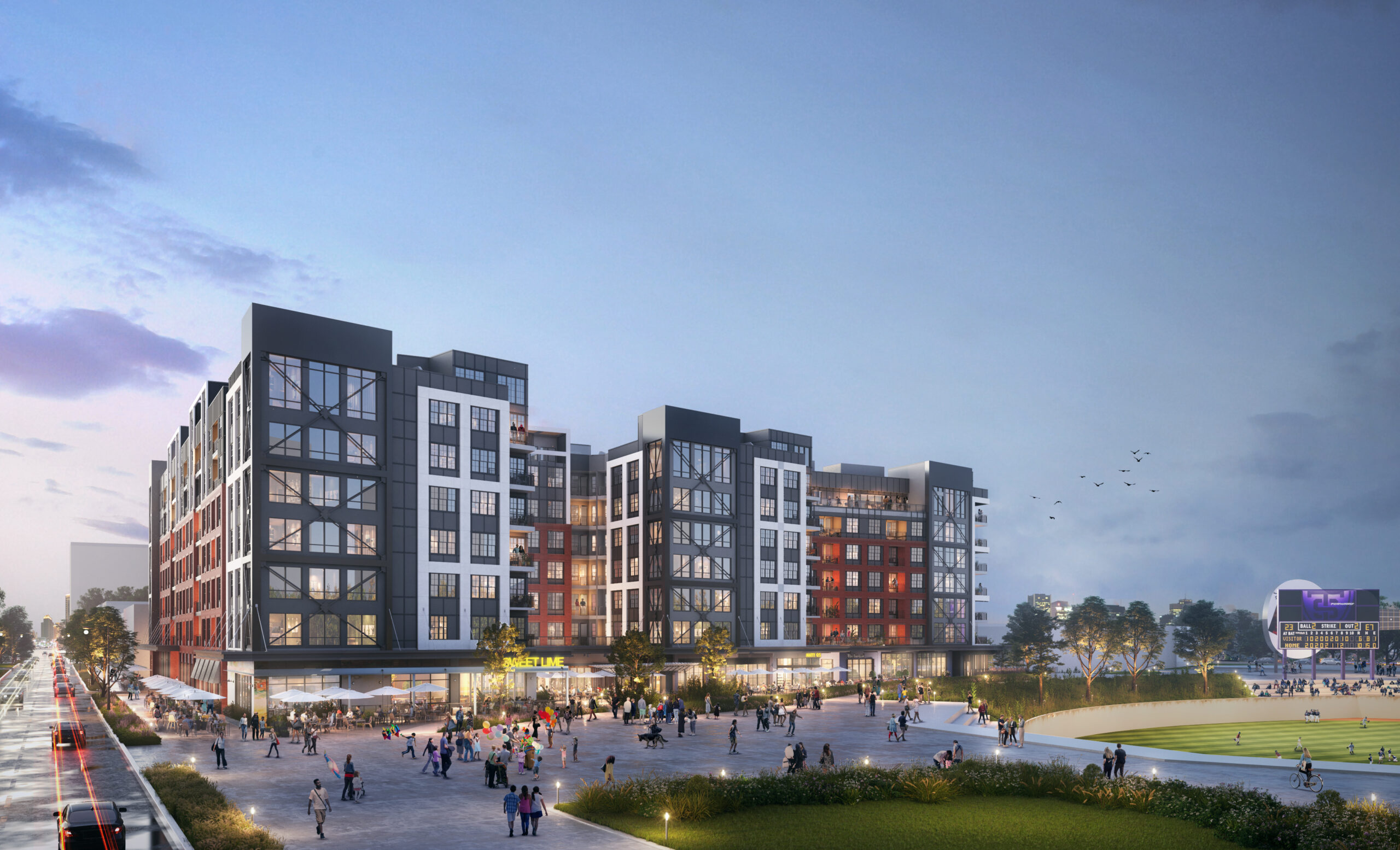 People are walking near apartment buildings. There is also a baseball field close by.