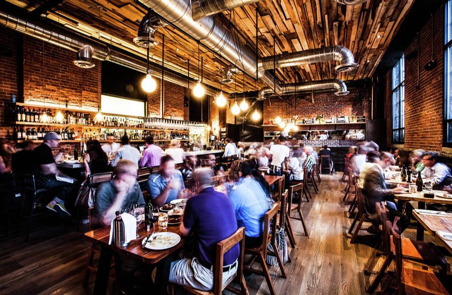 People sit at tables in a busy restaurant.