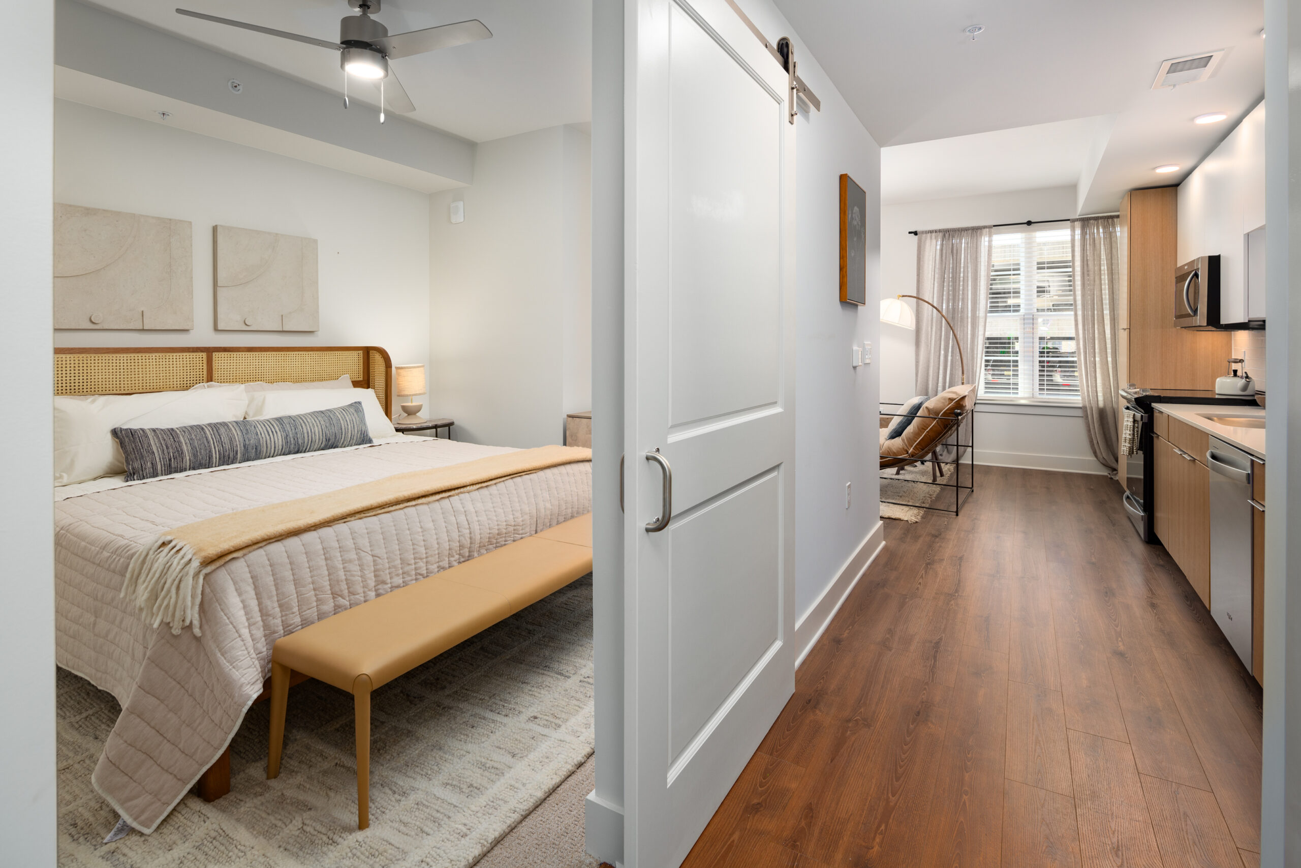 Model kitchen at our apartments for rent in Downtown Nashville, TN, featuring wood grain flooring and a view of the bedroom.